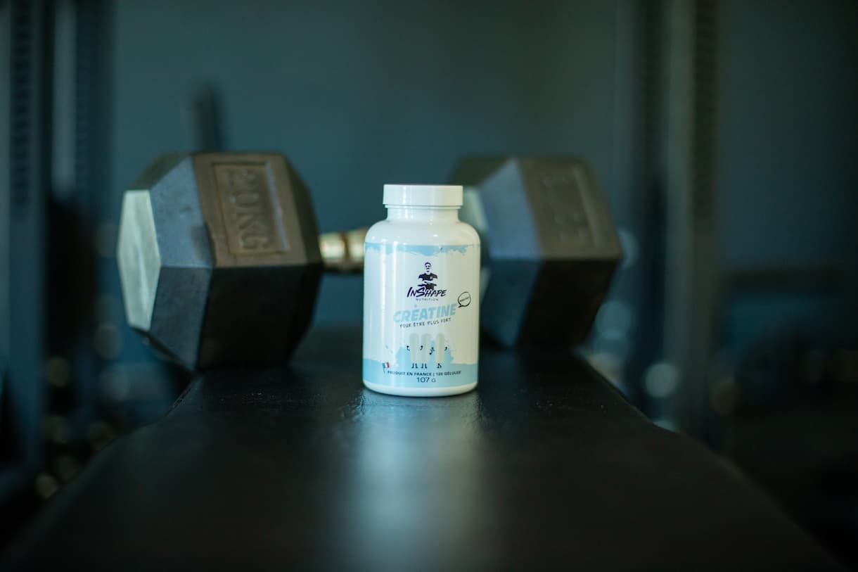 Creatin Inshape Nutrition vor einem Hantelständer gelegt